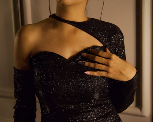 A close-up of neck  model wearing a sparkling black one-shoulder evening gown with a sweetheart neckline and long sleeves, evening dress