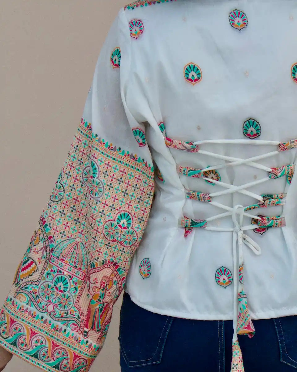 Back view of white corset lace-up top with tassel tie and multicolour woven motifs