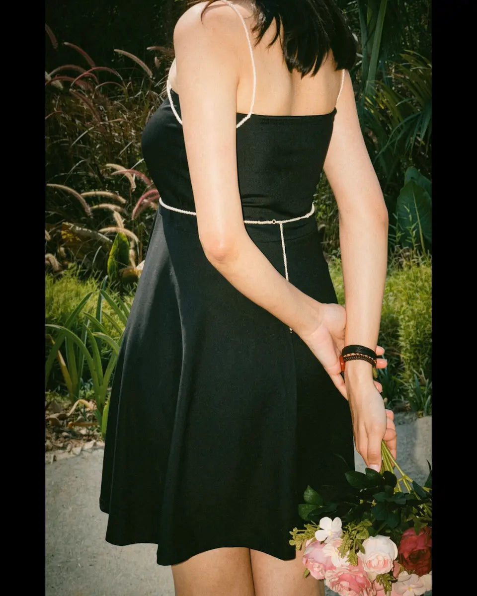 Model wearing Black mini tube dress with detachable beads accessories of shoulder and waist belt Back view image