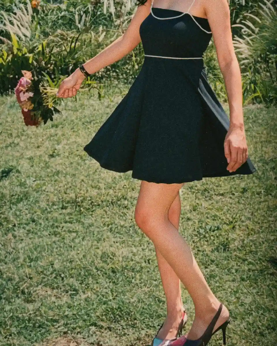 Model wearing Black mini tube dress with detachable beads accessories of shoulder and waist belt , sideview