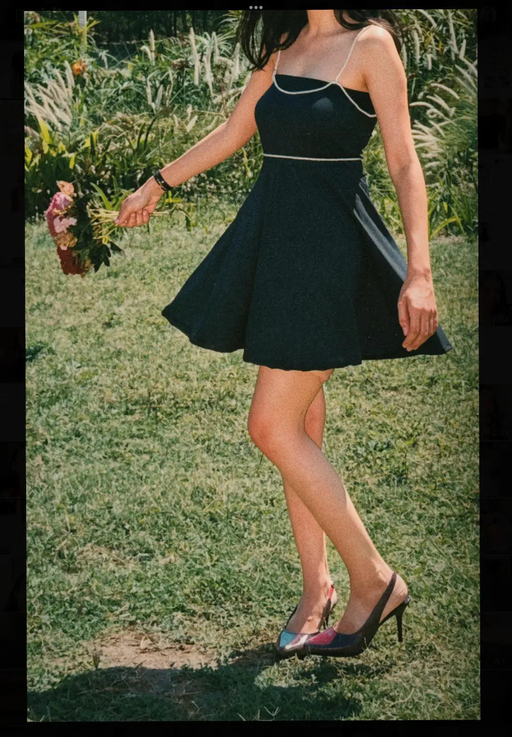Model wearing Black mini tube dress with detachable beads accessories of shoulder and waist belt , sideview