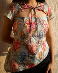 Pastel blue watercolor floral cut out top with tie-up neckline and cap sleeves, styled with black jeans