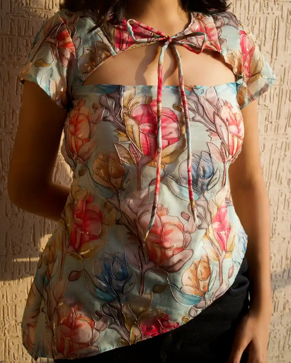 Pastel blue watercolor floral cut out top with tie-up neckline and cap sleeves, styled with black jeans