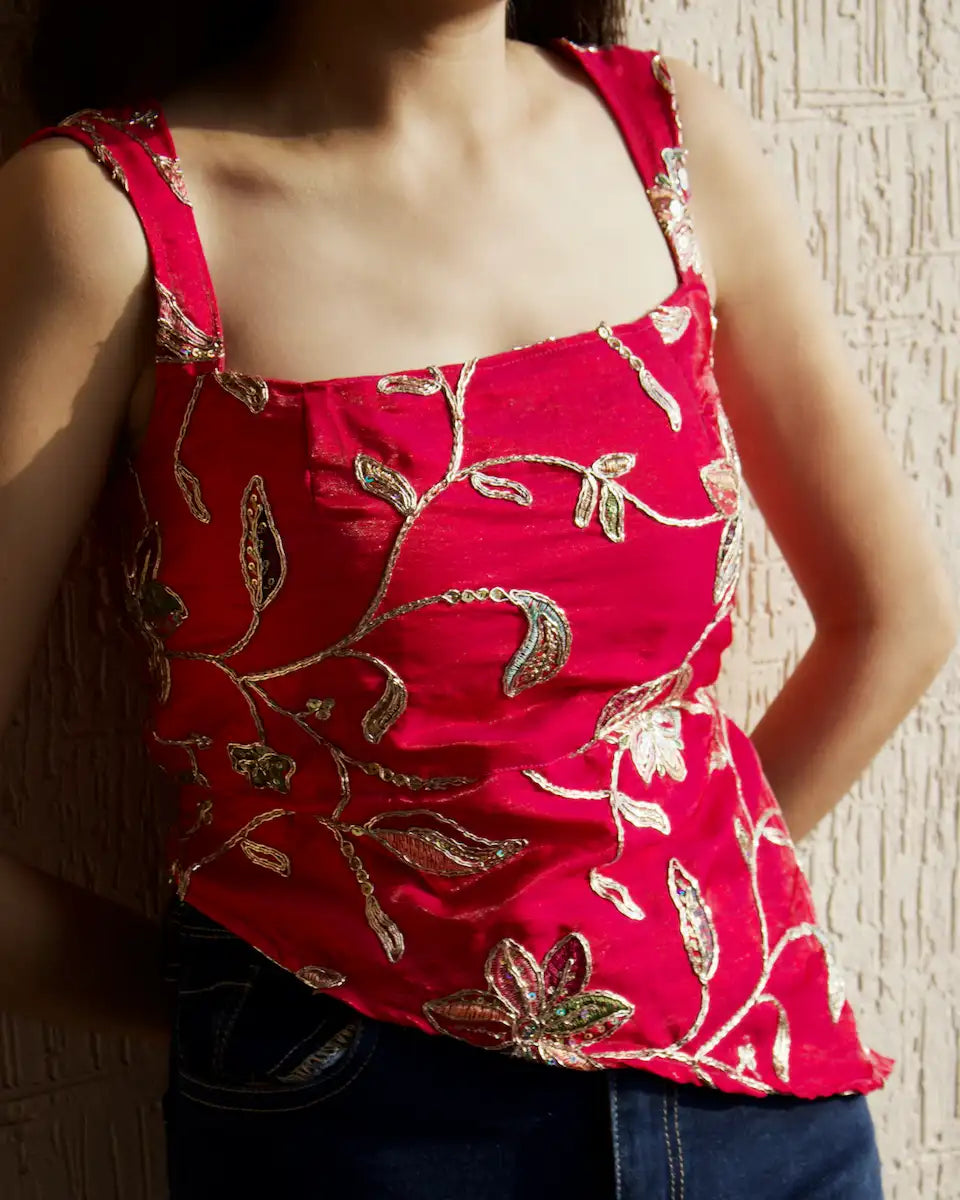 Dark pink embroidered square neck top with shimmery finish and asymmetric hem, styled with dark jeans side view